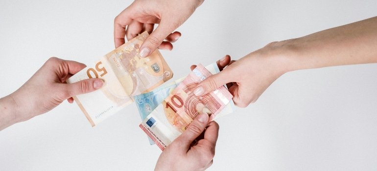 Multiple hands exchanging euro currency bills, showing how storage location affects pricing.
