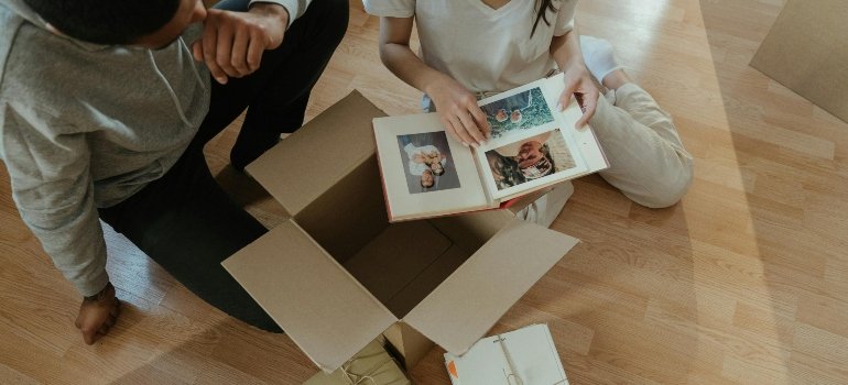 Two people seated on the floor, browsing pictures and organizing their move.