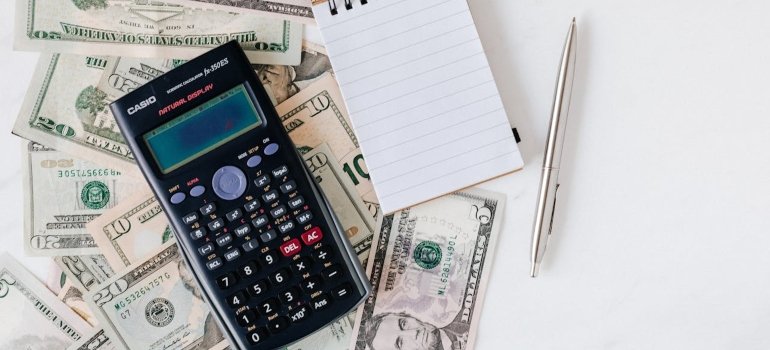 Calculator, notepad and money on a white surface as the budget is one of the things you need before renting an apartment in NYC.