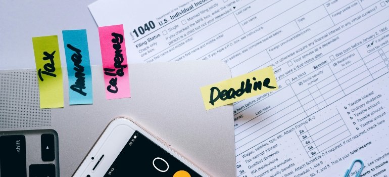 Sticky notes on laptop with tax terms and a 1040 tax form reminding users of tax deadlines.