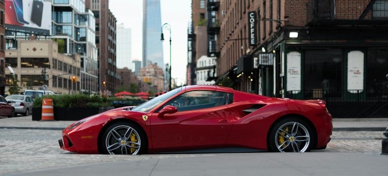Sleek luxury coupe parked on a paved street with tall buildings and shops behind it.