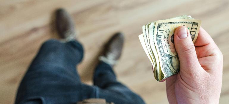 A person holding some money before deciding how long to store before tossing.