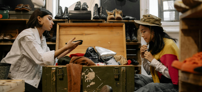 Two girls examining the content of an old crate with clothes.