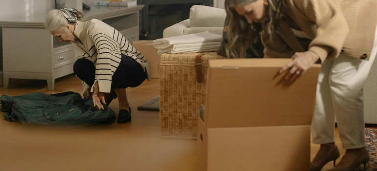 A mother and a daughter examining the contents of cardboard boxes.