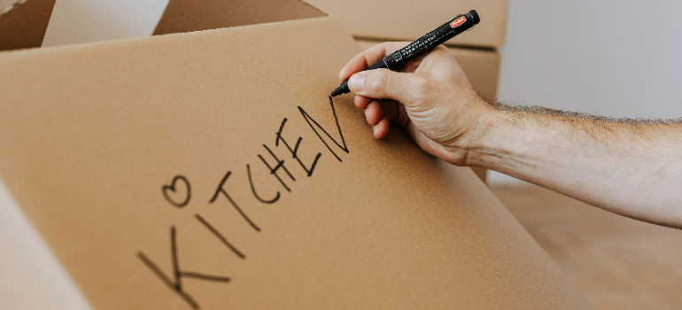 A person labeling a cardboard box.