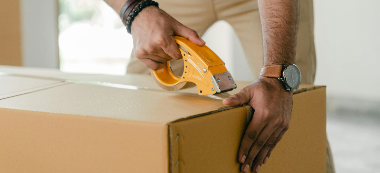 A person taping a cardbord box.