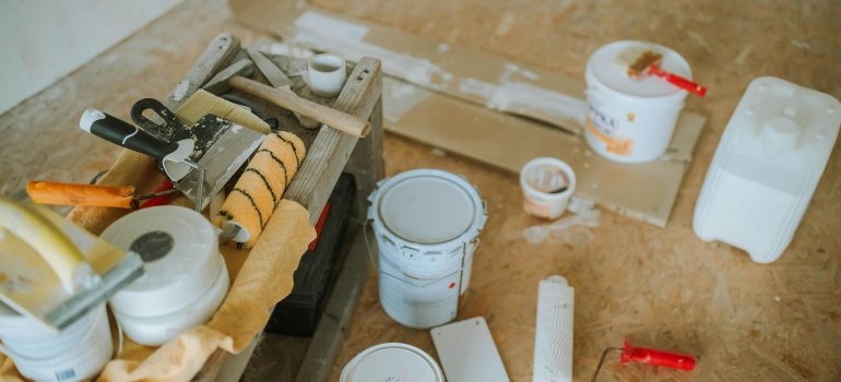 Painting tools, including buckets, trays, and rollers, arranged for a remodel.