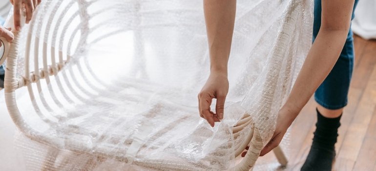 A person is wrapping a chair with bubble wrap.