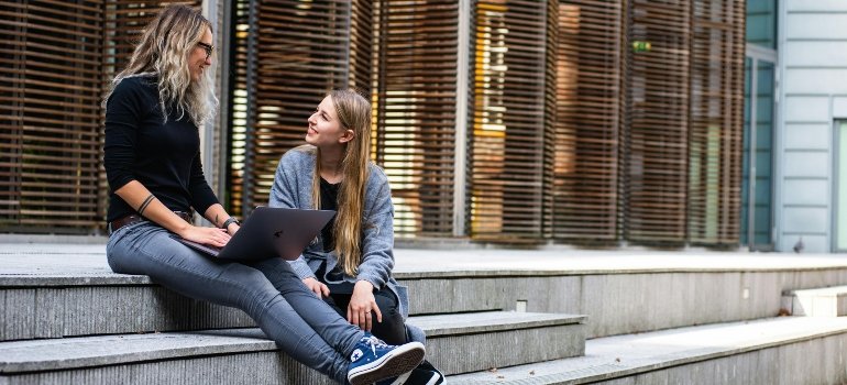 Students sitting on the stairs and trying to answer the question - Why should college students use self storage units?