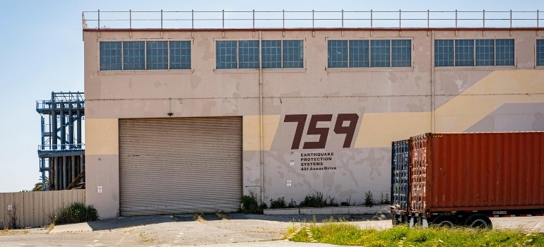 Exterior of a warehouse labeled 759, featuring earthquake protection systems and a large roll-up door.