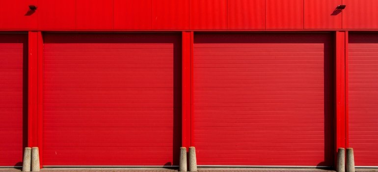 Row of vibrant red storage unit doors in direct sunlight.