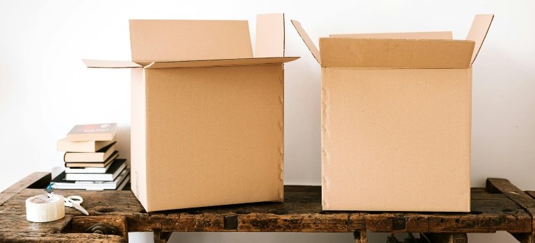 Two boxes next to a tape and some books.
