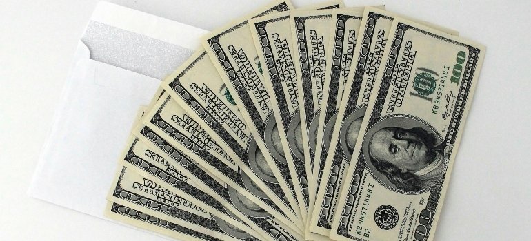 A fan of $100 bills spread out next to an open envelope symbolizing financial planning.