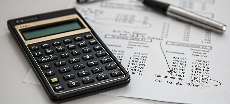A calculator, pen, and documents spread out on a desk to find the solution when struggling for space in New York.