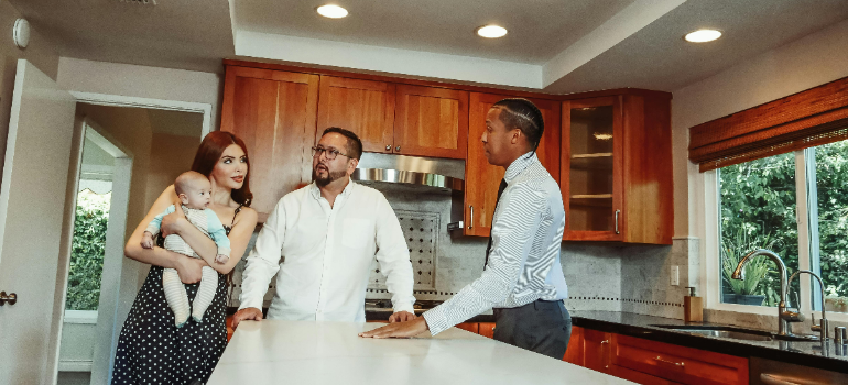 A family viewing an apartment with their baby and a real estate agent.