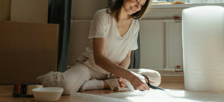 A woman packing boxes for moving to Manhattan with a newborn