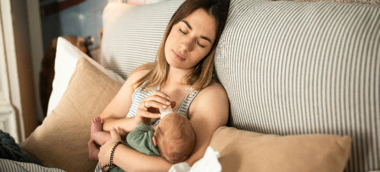 A mom falling asleep while feeding her baby.