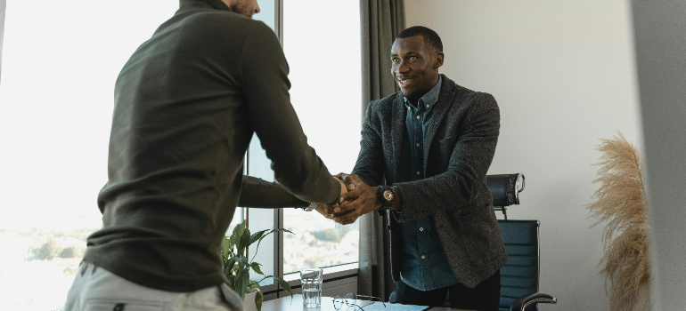 Two people shaking hands in an office.