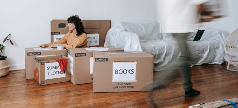 A woman packing items into labeled cardboard boxes while applying green storage practices.