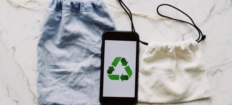 Eco-friendly bags and a mobile phone with recycling sign on it.