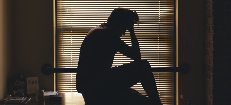A person holding their head while balancing mental health challenges during a relocation.