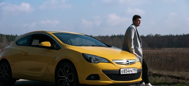 A man standing next to a yellow car