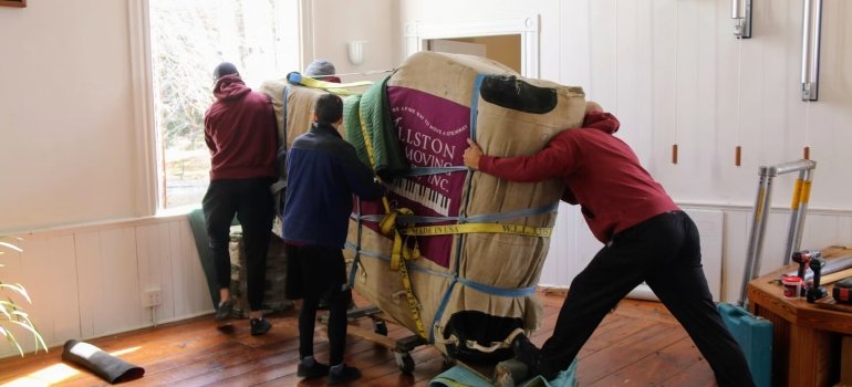A group of people carrying a large object nicely wrapped