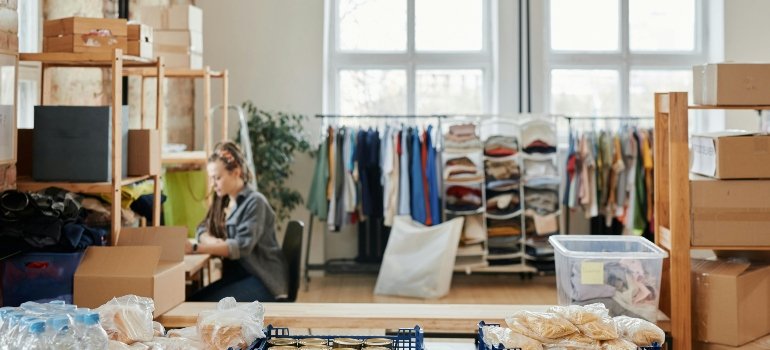 A woman sits in a storage room, thinking about best storage practices for businesses with limited office space in Queens.