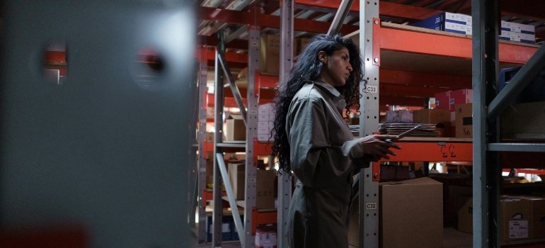A woman is checking the boxes for events in a storage unit, thinking about flexible storage options for event planning companies.