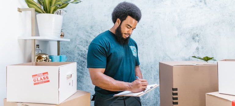 A mover checking the boxes, as a business owner should know before using storage in NYC what they are going to need to store.