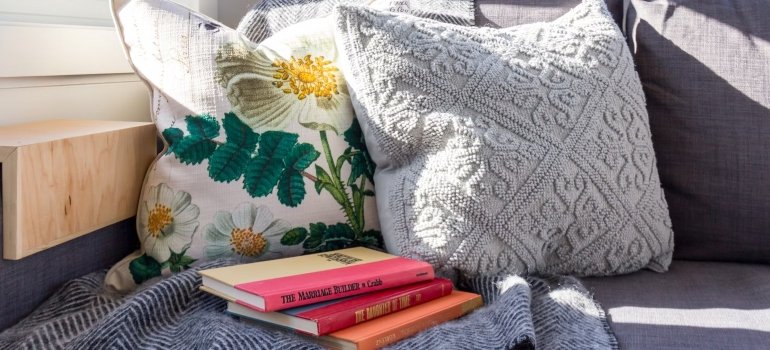 A stack of books and two pillows on a blanket, one of the decorating tips for your new Manhattan apartment is to add more personal touch