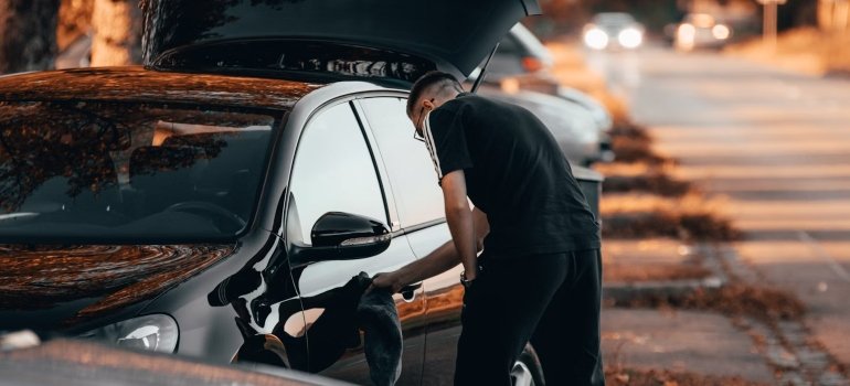 a man fixing or cleaning a car which is necessary when you choose long-term vehicle storage in NYC