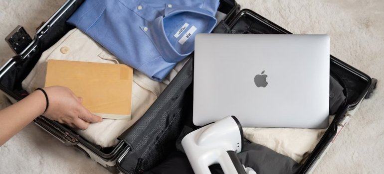 A packed and opened suitcase with clothes and a laptop
