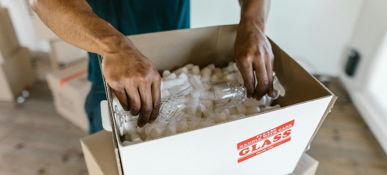 a man packing fragile items in a box ensuring all benefits of storage companies that offer pickup services are met