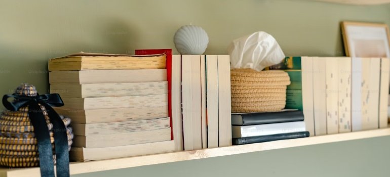 A shelf with books and a ball of yarn, using shelves as one of the decorating tips for your new Manhattan apartment