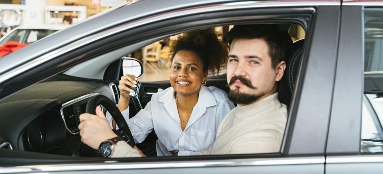 A man and a woman are sitting in the car, talking about how to maintain your vehicle during long-term storage.