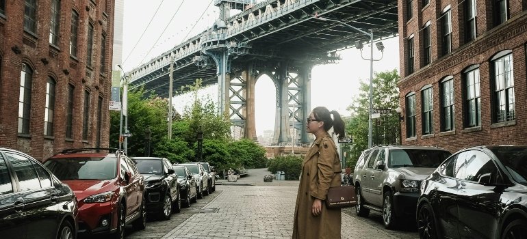 A woman is standing on the street and thinking about how to enjoy summer in Manhattan.