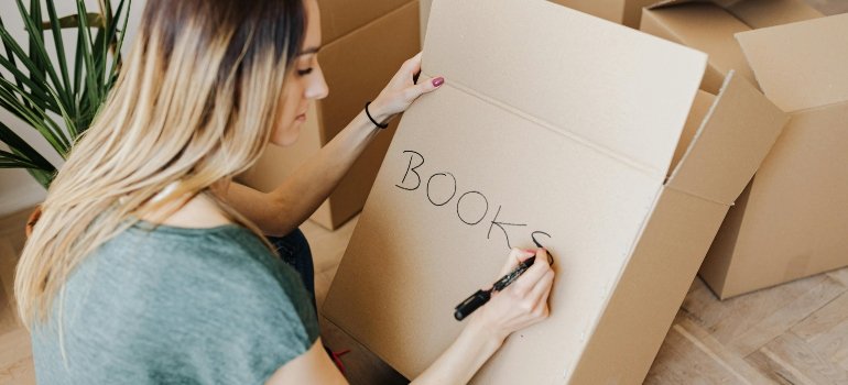 a girl writing something on the box in order to customize your new apartment in NYC