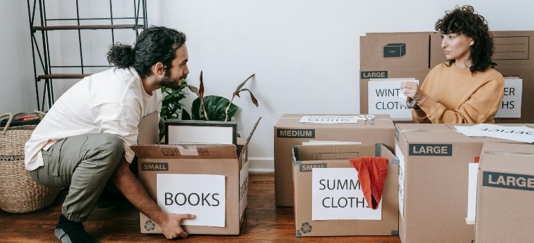 Man and woman sorting and labeling boxes like "Books" and "Summer Clothes" during a Last-Minute Summer Move in NYC.