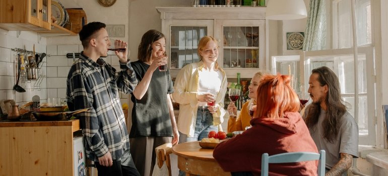 Group of roommates enjoying a drink and conversation in a cozy kitchen on moving day.