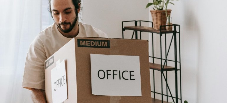 A man is carrying an office box to a new place.
