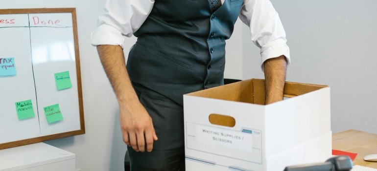 A man is packing his office stuff in the white box, thinking about how to use business storage to free up expensive office space.