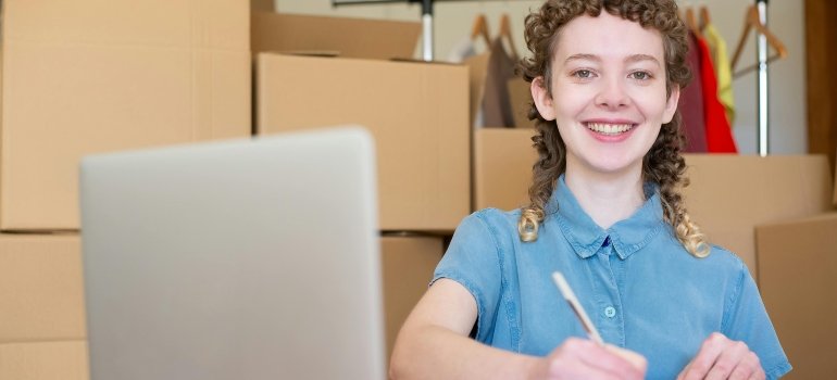 A smiling woman is writing notes on paper about how to use business storage to free up expensive office space.