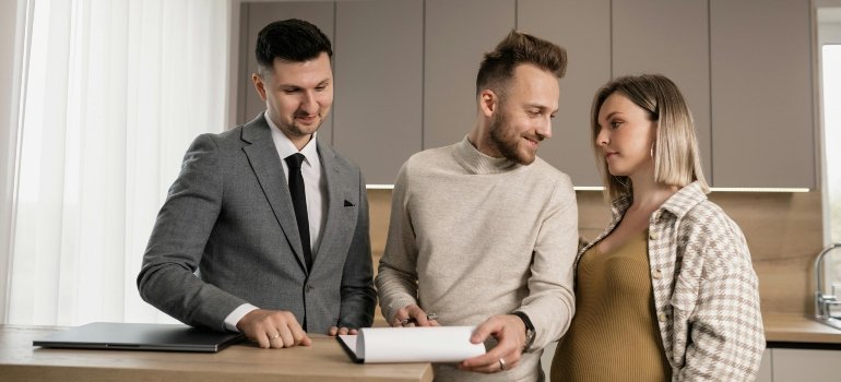 Storage tips for expecting parents shown with expecting parents and a moving professional signing a contract.