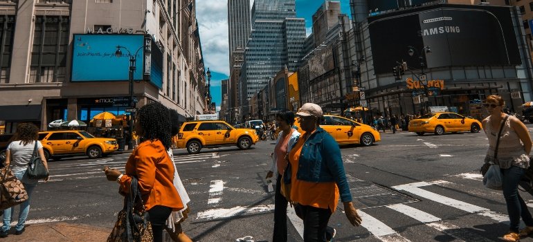 usy Manhattan street filled with yellow cabs and people crossing in every direction.
