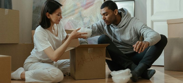 Man and Woman Sitting on the floor and packing