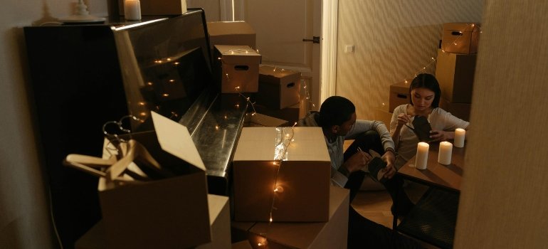 Couple seated among boxes and candlelight in their new apartment, transitioning into a new home.