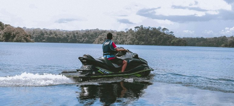 Person riding a jet ski on a peaceful lake, showcasing Storing Summer Equipment Safely.