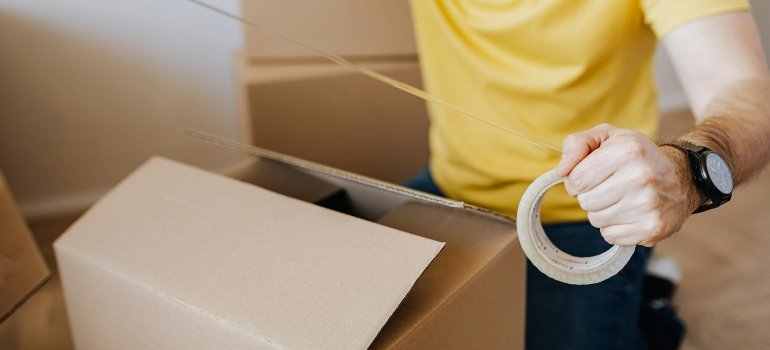 Crop man with cardboard boxes while packing belongings