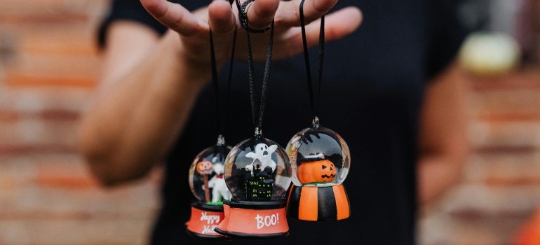 Hand holding Halloween ornaments while moving into a new home.